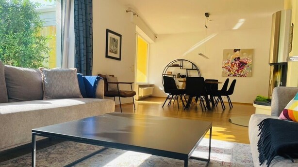 A living room with a sofa, a coffee table, a dining table with chairs, and a painting on the wall. - Detached single-family home above the rooftops of Bad Dürkheim (Bad Dürkheim)