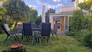 A patio with outdoor furniture, a stone table, and a garden with trees and a building in the background. - Detached single-family home above the rooftops of Bad Dürkheim (Bad Dürkheim)