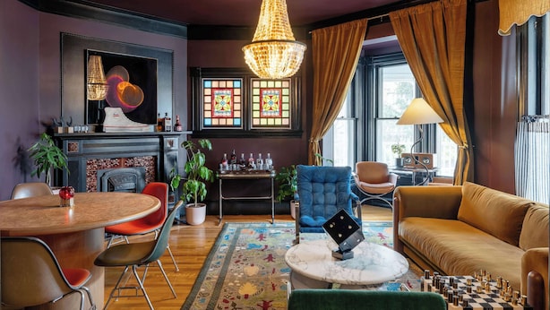 A room with a chandelier, a fireplace, a dining table, a sofa, and a chessboard. - The Turret - Ash Street Inn (Manchester)