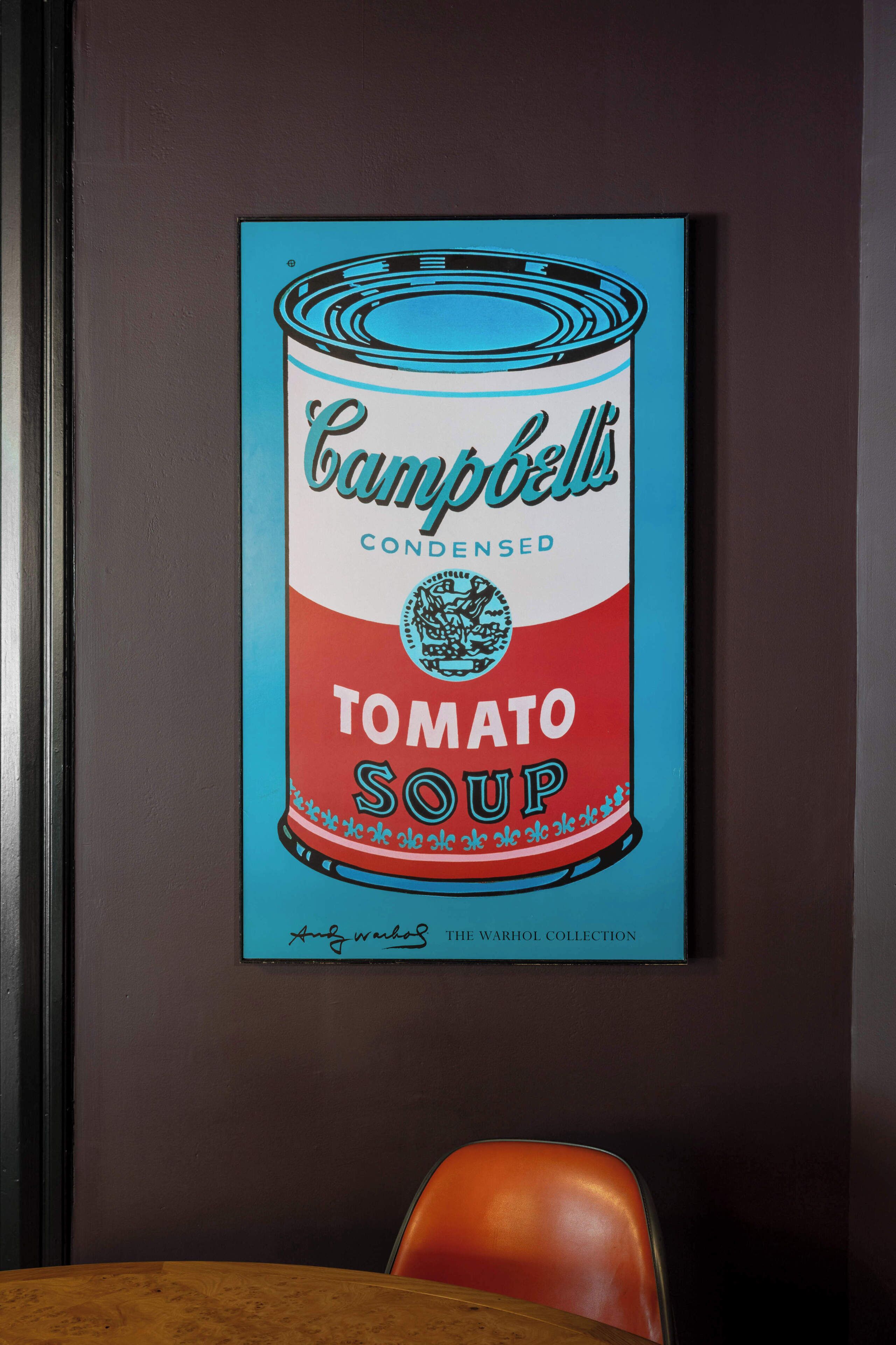 A framed artwork of Campbell's Condensed Tomato Soup on a dark wall.