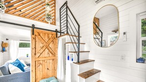 Ein modernes Interieur mit einer Holztreppe, einer Spiegelwand und einer gemütlichen Sitzecke.