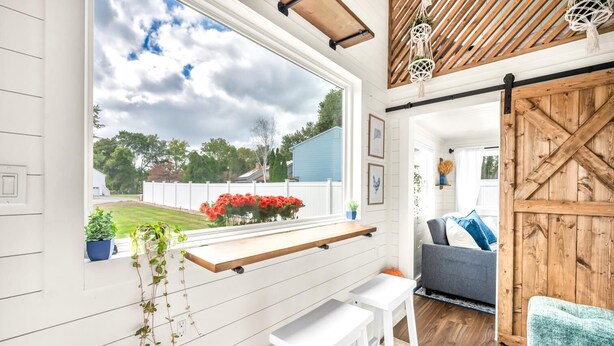 Ein gemütliches Wohnzimmer mit großem Fenster, Holzboden und einer rustikalen Scheunentür.