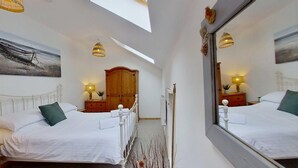 Un dormitorio con dos camas, un armario de madera, un espejo y un tragaluz.