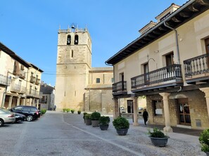 Una plaça antiga amb paviment de lladrics, una torre destacada i edificis tradicionals amb balcons.