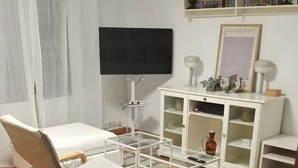 Un salon comprenant un canapé, un fauteuil, un téléviseur, un meuble et un plancher en bois.