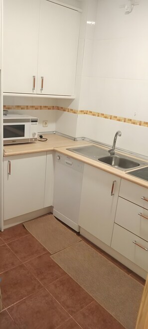 Eine Küche mit weißen Schränken, einer Mikrowelle, einem Spülbecken und einem Geschirrspüler.