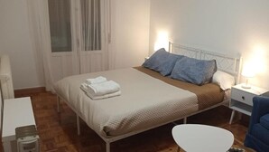 Une chambre à coucher comprenant un lit, deux tables de chevet, une chaise et une petite table.