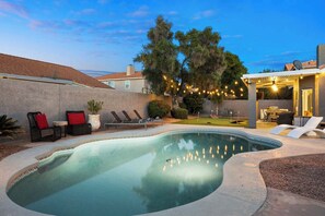 A backyard with a swimming pool, lounge chairs, and a patio area with string lights. - LUX Modern Escape: Pool, Putt, Kierland Commons (Scottsdale)