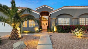 A two-story house with a central entrance, a driveway, and a landscaped garden with palm trees and cacti. - LUX Modern Escape: Pool, Putt, Kierland Commons (Scottsdale)