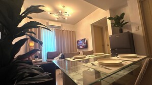 Un comedor moderno con una mesa de vidrio, sillas y un televisor montado en la pared.