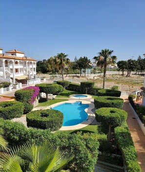 A resort with a swimming pool surrounded by well-manicured bushes and palm trees. - cozy vacation apartment in Vera (Almeria)