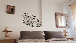Un dormitorio con una cama, dos mesitas de noche, un adorno en la pared y un espejo.
