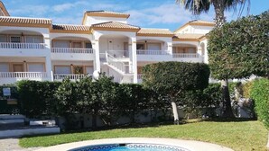 Una piscina con borde de azulejos, rodeada por un camino de piedra y césped.