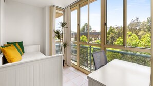 A balcony with a white table and a white bench with cushions. - Green Views & Great Location: Inner-city 1-bed (Sydney)