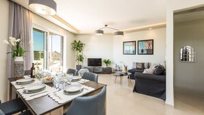 Un salon moderne comprenant un coin repas, un ensemble de canapés et un téléviseur à écran plat.