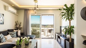 Un salon moderne avec un canapé, une table basse et des plantes en pot. Il y a un balcon avec vue sur le paysage.