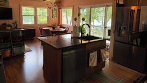 Una cucina con isola centrale, soffitto in legno, ampie finestre e vista sull'esterno.
