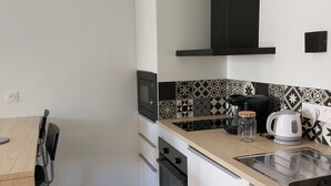 A compact kitchen with a microwave, oven, and a coffee maker on the counter. - Ty PenAr Pont étage (Saint-Pol-de-Léon)