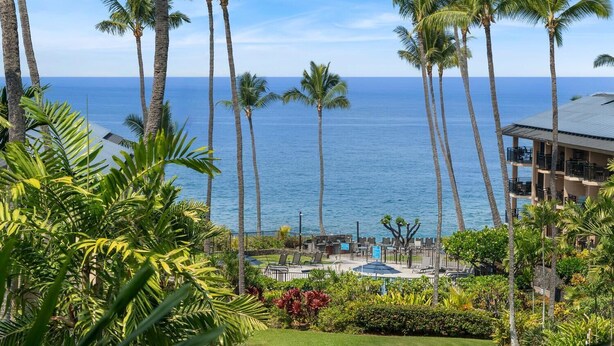 A resort with a pool area, palm trees, and a view of the ocean. - Great Location AC & Wifi Concierge Included! (Kailua-Kona)