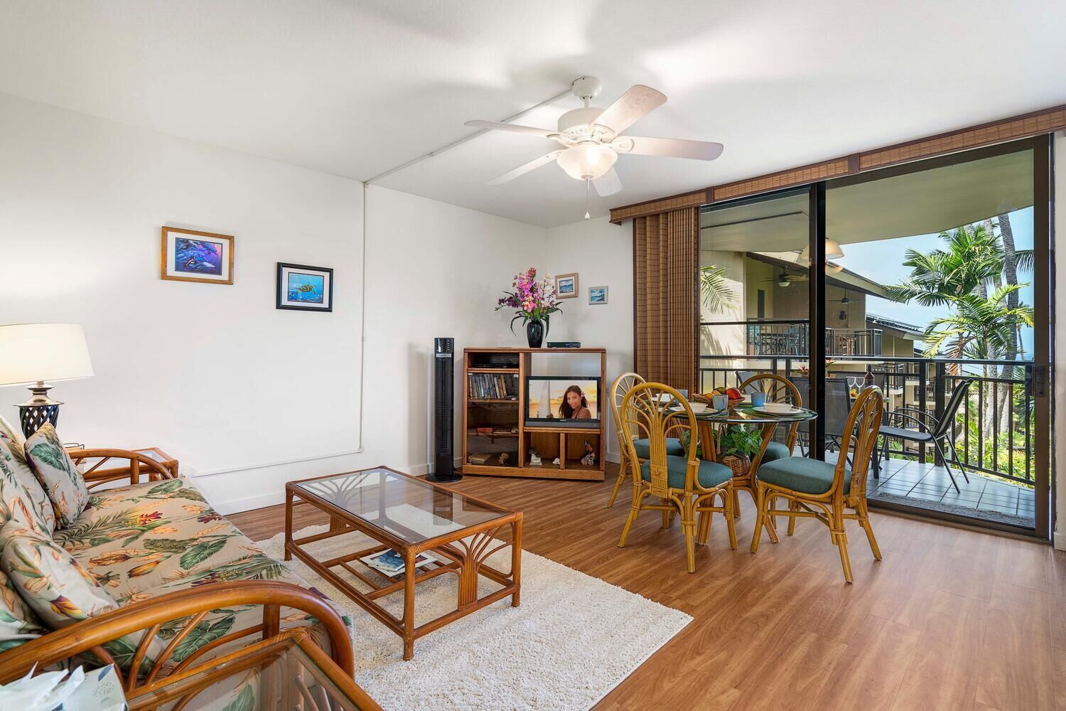 A spacious living area with a balcony, a ceiling fan, and a view of the outdoors.