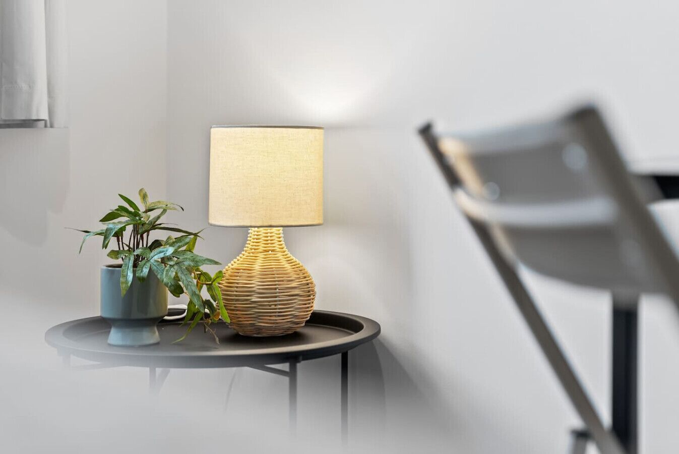 En modern lampa med en strukturerad fot och en fyrkantig lampskärm, placerad på ett litet bord.