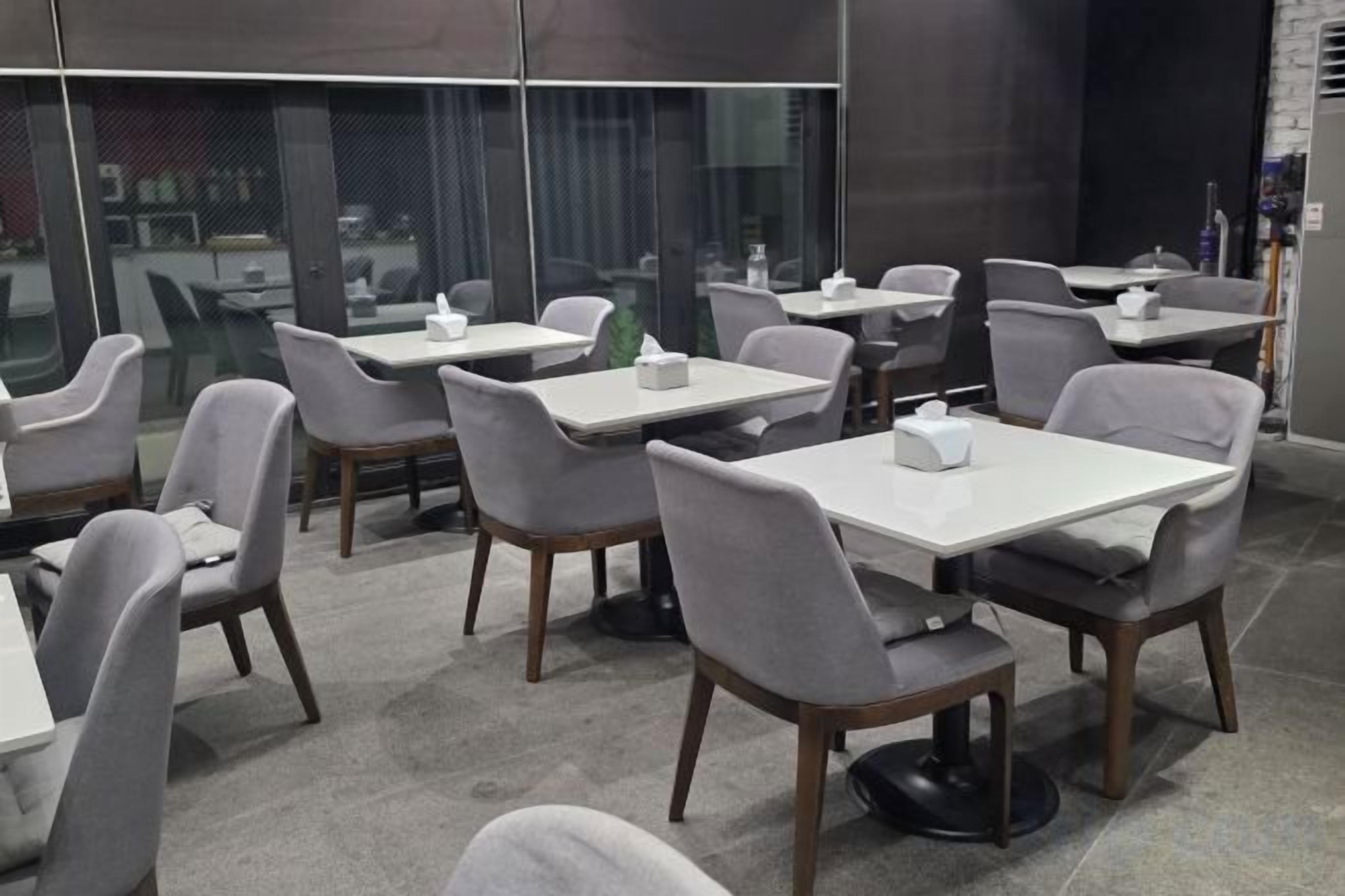A modern dining area with tables and chairs, large windows, and a view of the city.