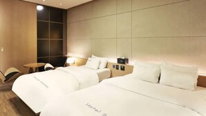 A hotel room with two beds, a small table, and a seating area. - Bolton Hotel (Gwangju)