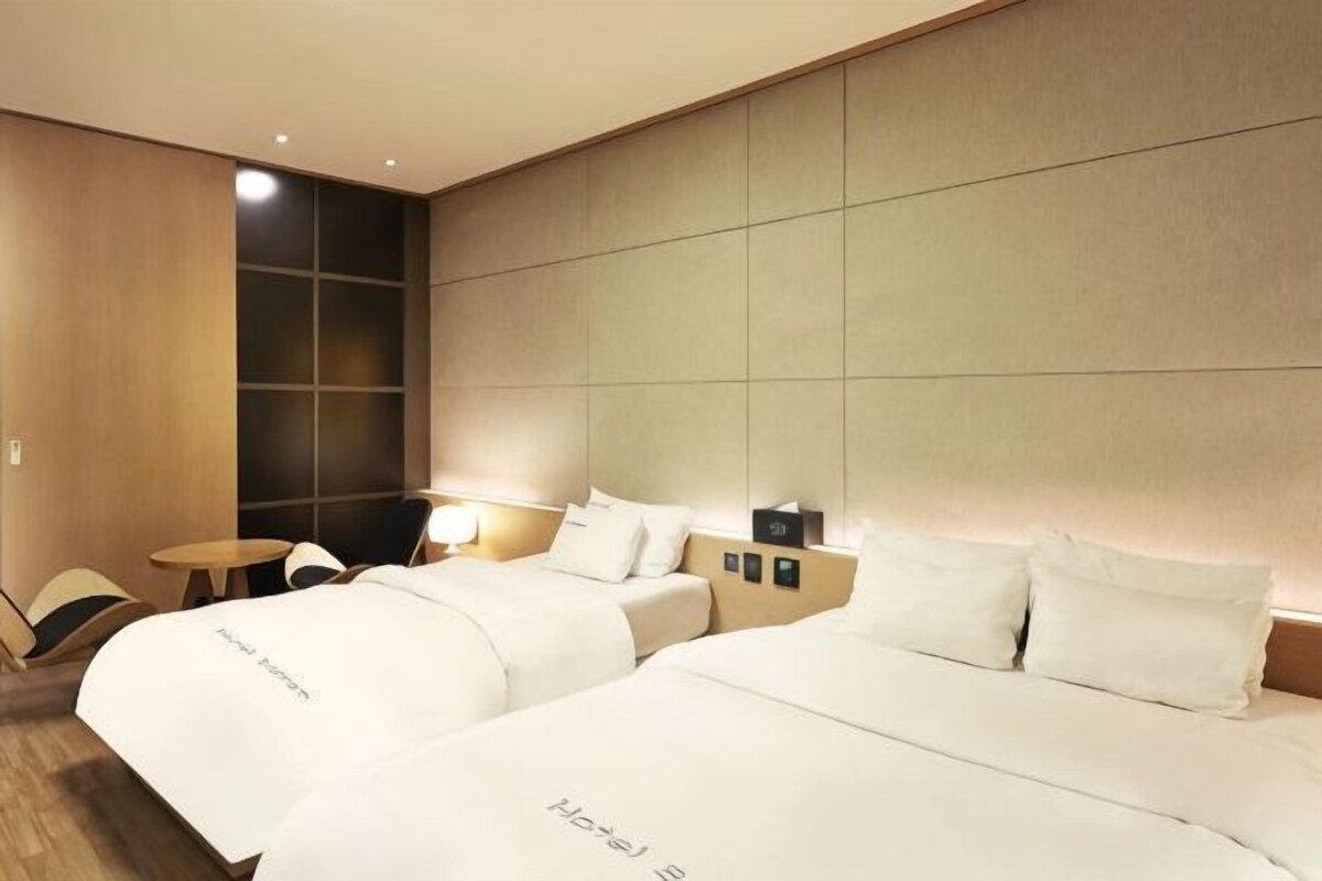 A hotel room with two beds, a small table, and a seating area.