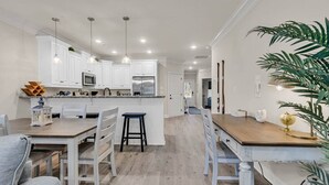 A modern kitchen with white cabinetry, stainless steel appliances, and pendant lighting. - Yellow Fin Retreat (Murrells Inlet)