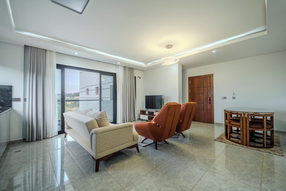 Una sala de estar moderna con un sofá, dos sillones, un televisor y una mesa de comedor.