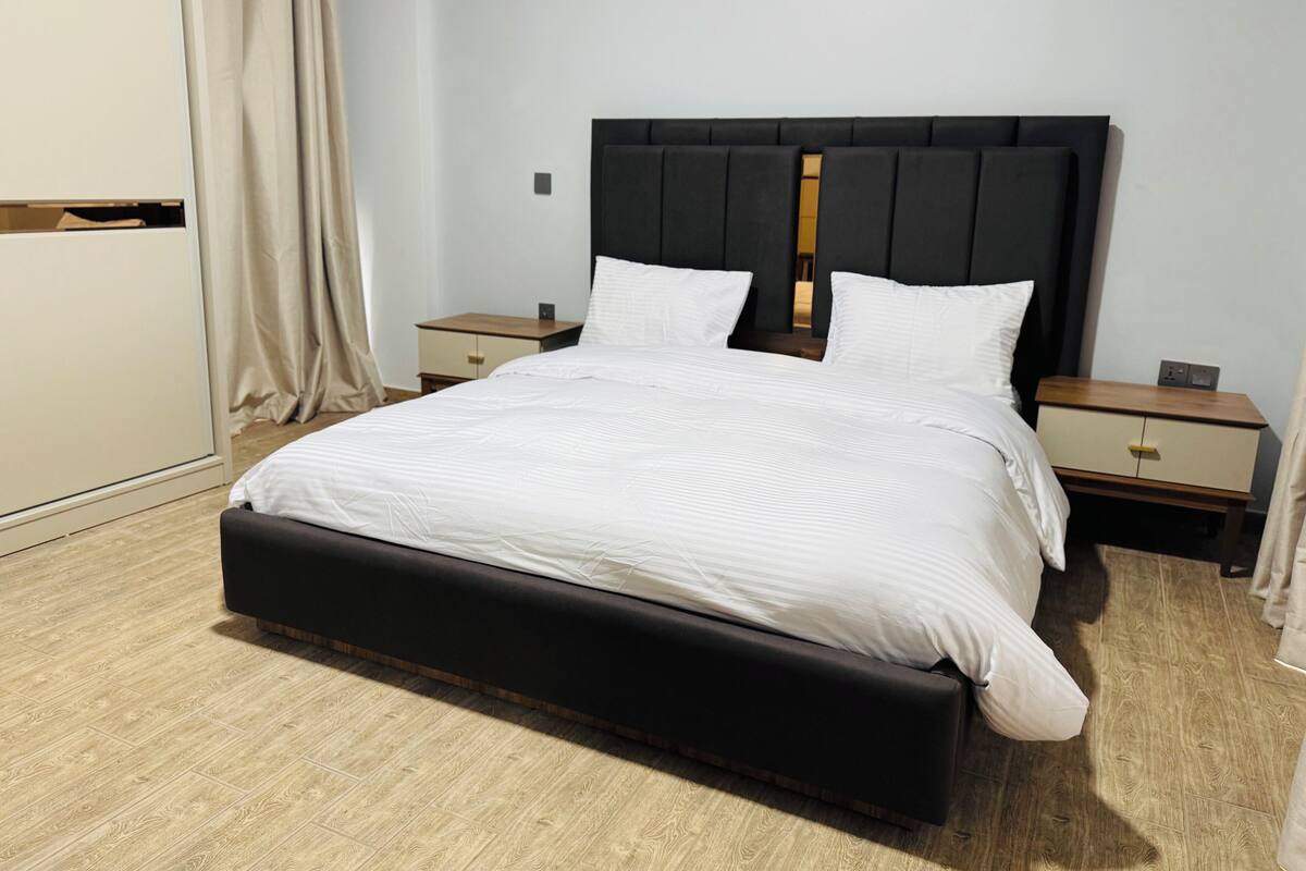Una habitación de hotel moderna con una cama grande, dos mesitas de noche y un armario.