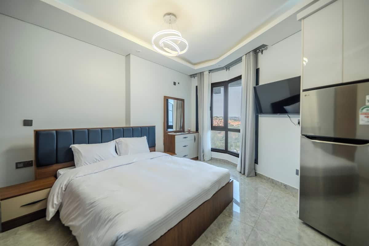Un dormitorio moderno con una cama grande, un armario empotrado, un televisor de pantalla plana y vistas al exterior.