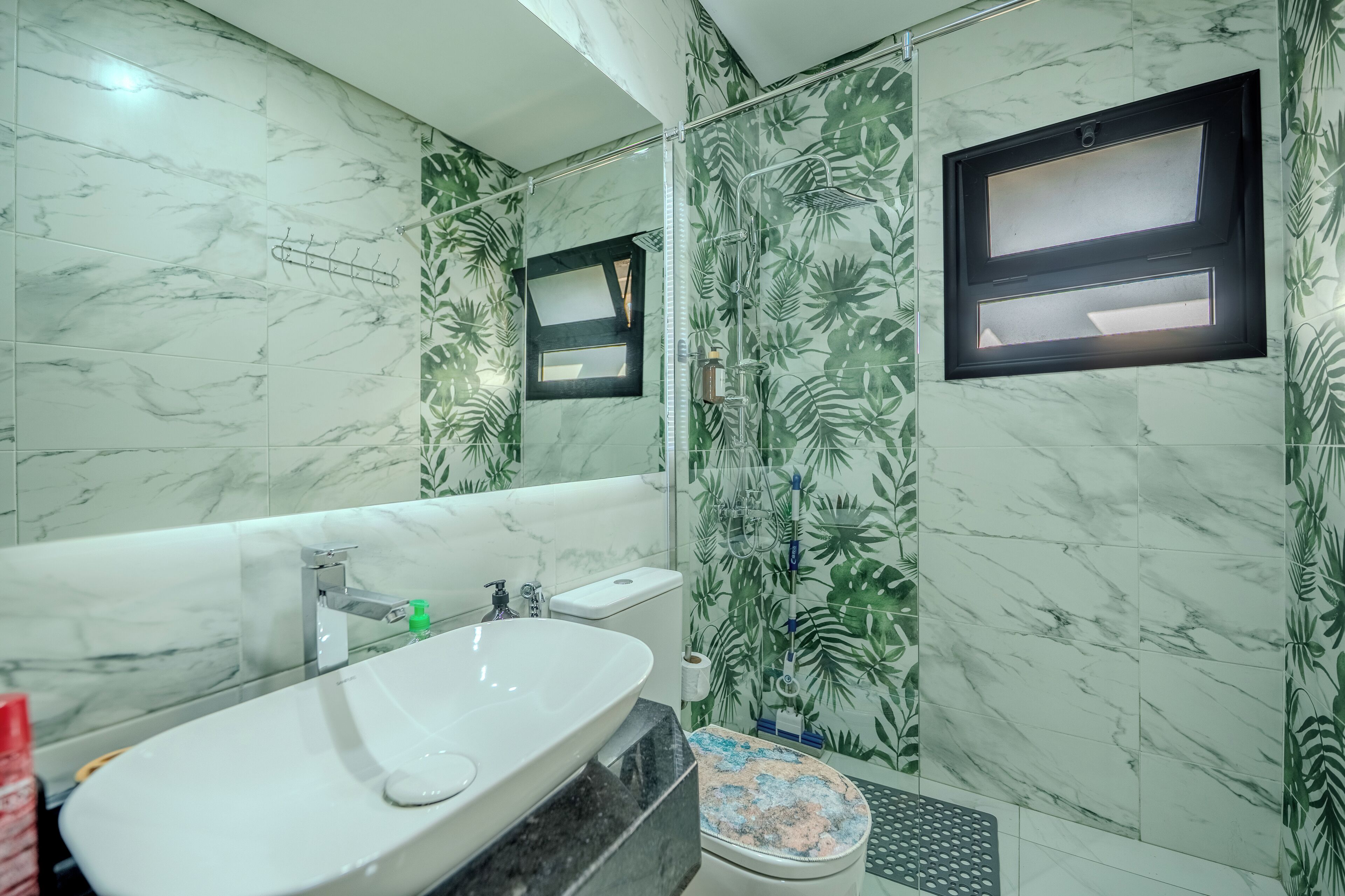A bathroom with a marble sink, a toilet, and a shower with a glass door.