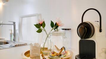 Eine Küchenarbeitsplatte mit einer Kaffeemaschine, zwei Glasbehältern, einer Serviertablett und einem Dekoelement.