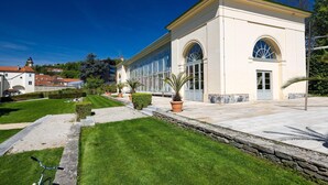 A building with a large arched window, a stone wall, and a well-maintained lawn. - Arcadio Home - Smart Suite (Graz)