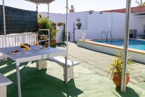 Une terrasse avec une table mise pour le petit-déjeuner, une piscine et des plantes en pot.