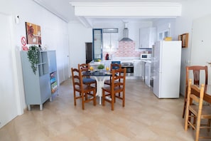 Eine moderne Küche mit Essbereich, weißen Schränken und Fliesenboden.