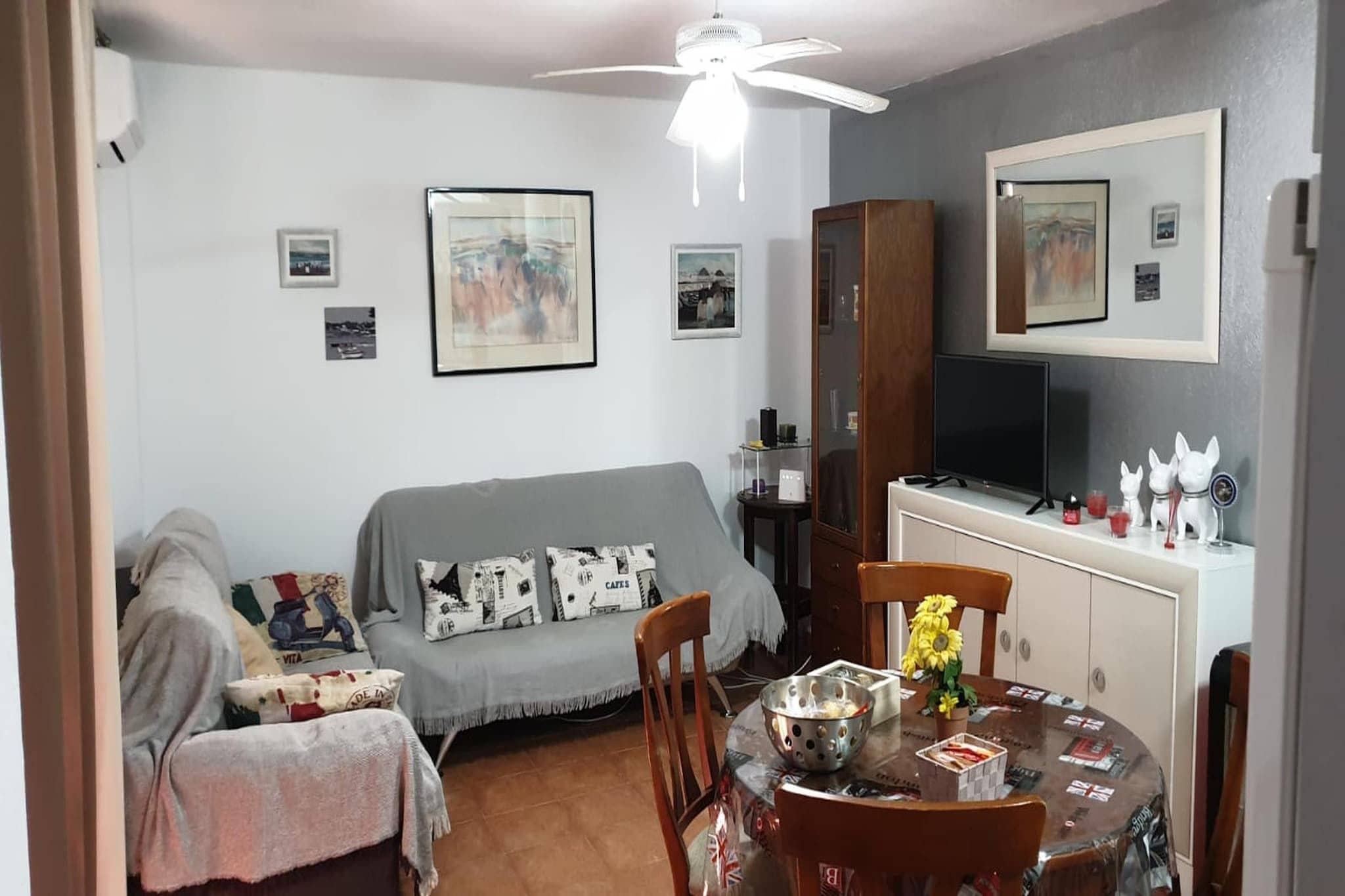 Un coin repas comprenant une table ronde, des chaises, un téléviseur et un ventilateur de plafond.