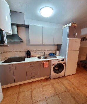 A compact kitchen with a sink, stove, and a built-in washing machine. - Nice apartment in Natura World, Almeria (Almeria)