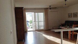 A spacious living area with a sliding glass door leading to a balcony, a dining table with chairs, and a ceiling fan. - Perfect Getaway in Vera (Almeria)