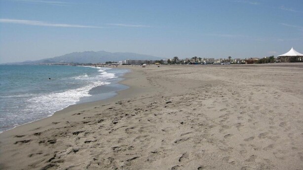 A beach with footprints, a tent, and buildings in the background. - Apartment near Vera Naturist Beach (Almeria)