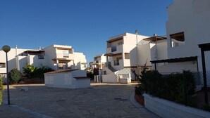 A residential area with modern white buildings, a paved courtyard, and a clear blue sky. - Apartment near Vera Naturist Beach (Almeria)