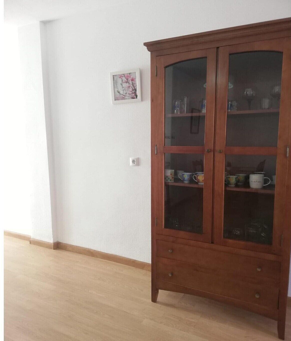 Un meuble en bois doté de portes en verre, renfermant des ustensiles de cuisine.