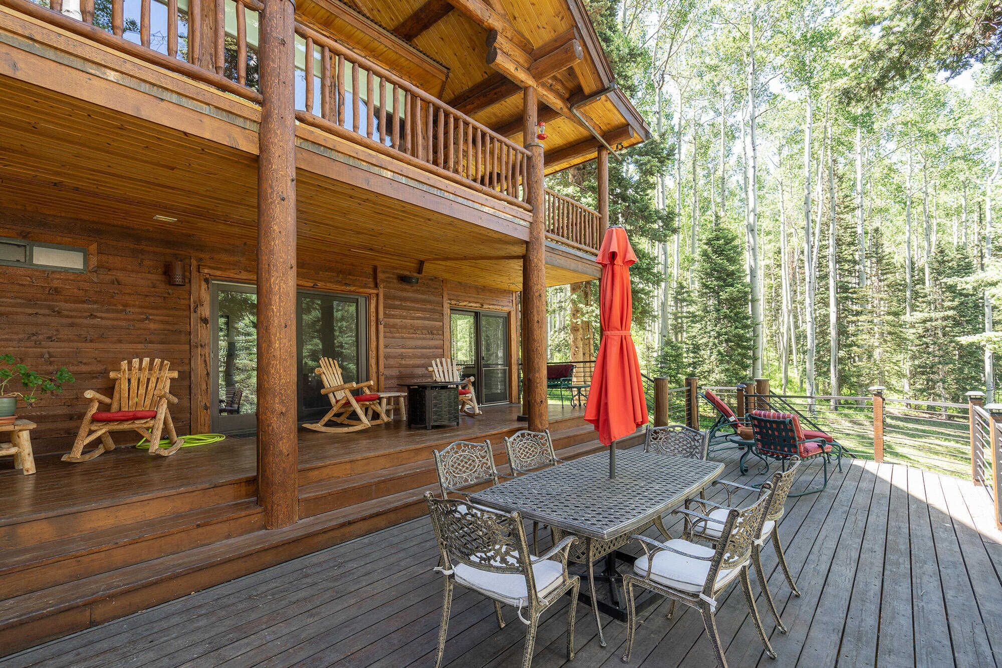 Une cabane en bois dotée d’un porche abrité, de meubles d’extérieur et offrant une vue sur une forêt.