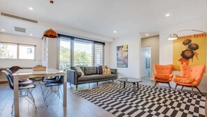 A modern living room with a dining area, a sofa, two armchairs, a coffee table, and a checkered rug. - Cosy 1-bedroom Apartment Close to the City (Sydney)
