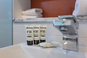 Un lavabo de salle de bain avec trois bouteilles de gel douche de la marque Biology et un savon.