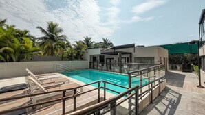 A swimming pool with a glass barrier, lounge chairs, and palm trees. - 5 minutes from Macumba Beach | ZV101 (Rio de Janeiro)