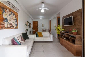 A living room with a white sofa, a wooden TV stand, and a ceiling fan.
