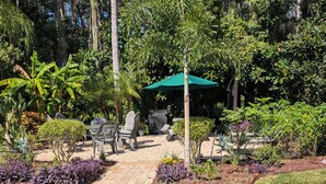Een terras met buitenmeubels, een overdekte barbecue en weelderige beplanting.