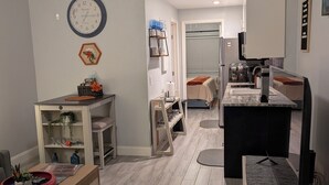 Een moderne woonkamer met houten vloer, een eethoek met een marmeren tafel en een keuken met een zwart aanrecht.
